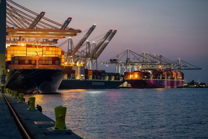 Container ships berthed under quay cranes at a port terminal at dusk