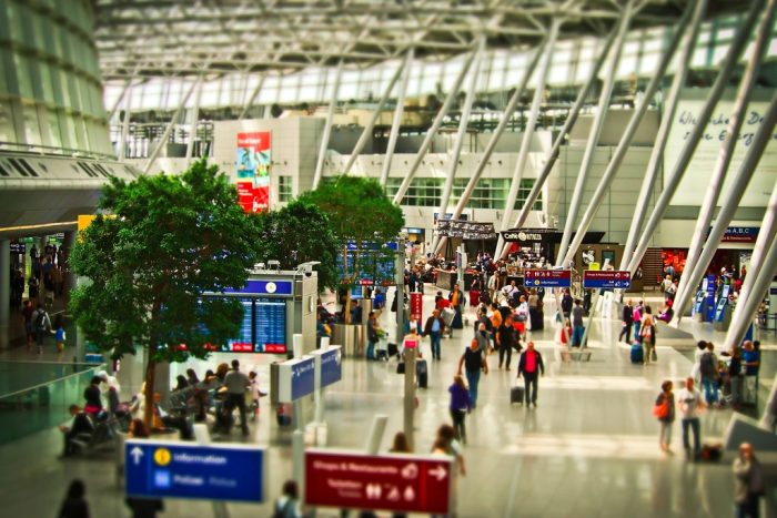 Passengers in a modern airport terminal concourse under a glazed roof